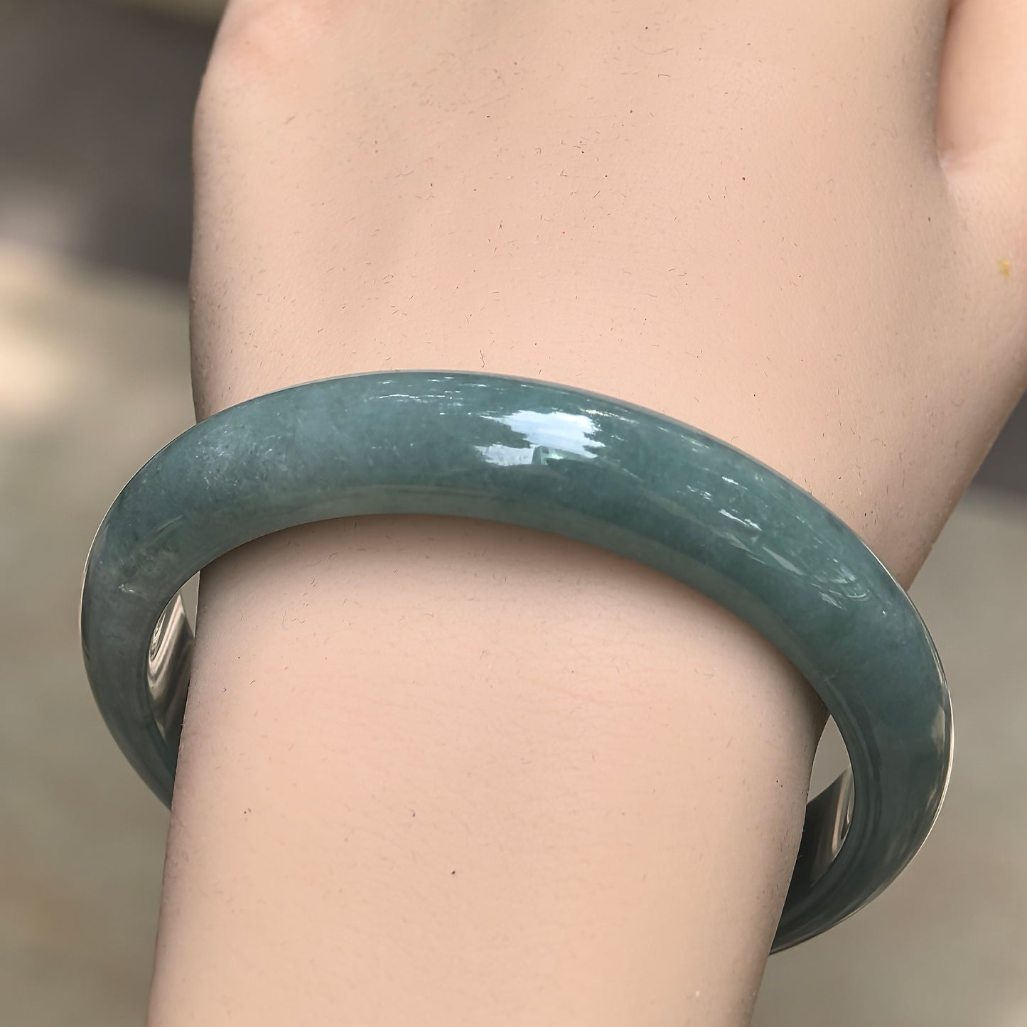 Close-up of oil-green jadeite bangle showing smooth polish and soft natural luster.
