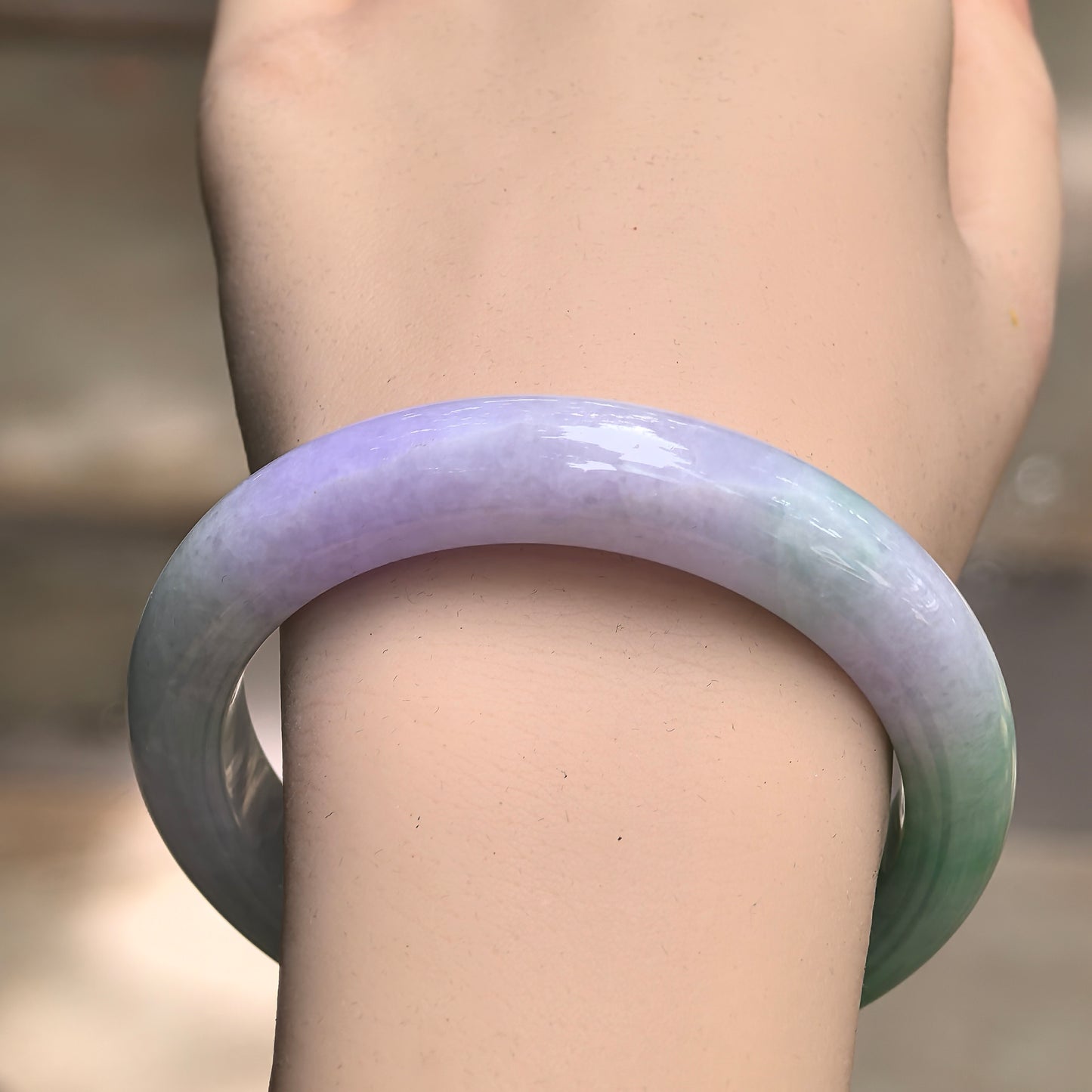 Close-up of green and lavender jadeite bangle showing rich color and smooth polished luster.
