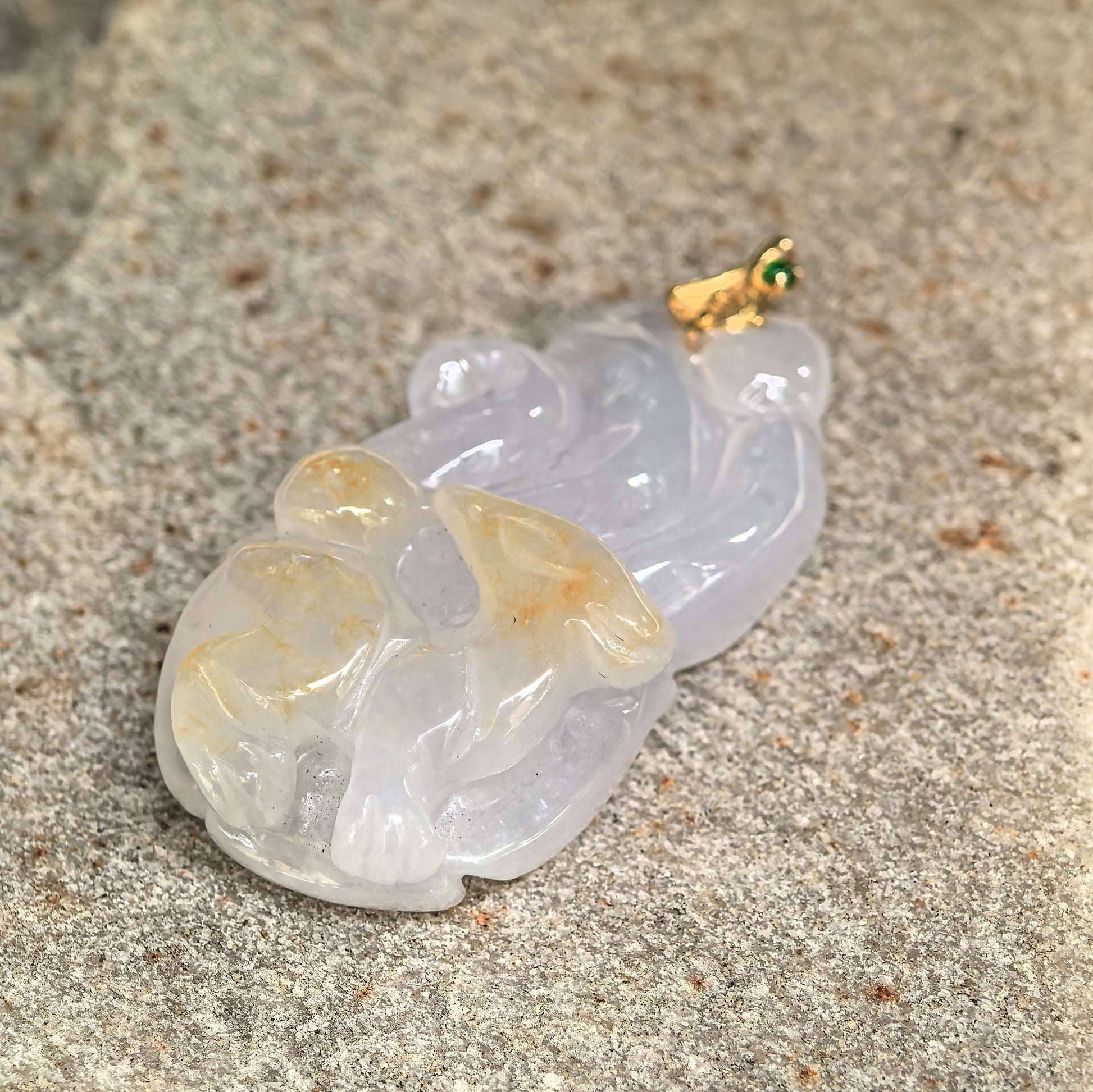 Natural Grade-A lavender-white jadeite pendant displayed on stone surface showing tail carving details.
