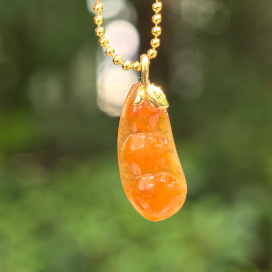 Natural Grade-A icy glutinous orange-red bean jadeite pendant hanging under natural light.
