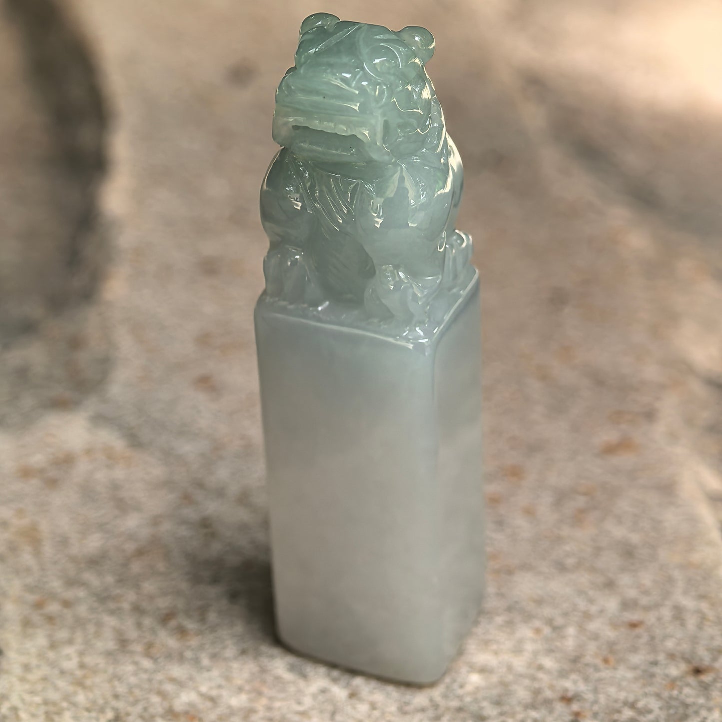 Close-up of light green jadeite lion seal ornament showing polished rectangular seal body.
