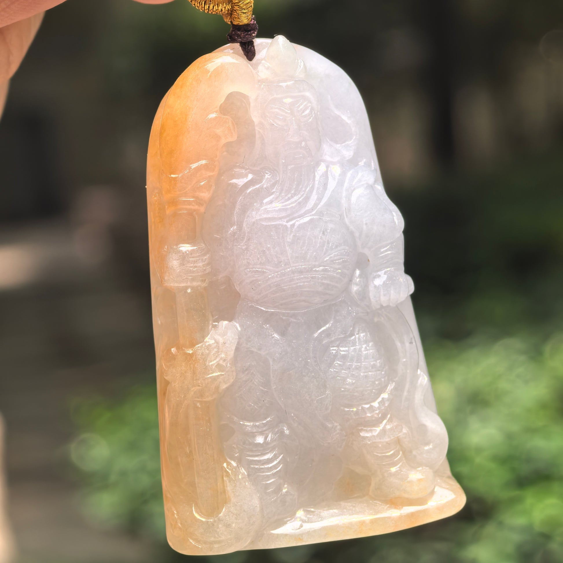 Natural Grade-A glutinous white and yellow Guan Gong jadeite pendant hanging in natural light.

