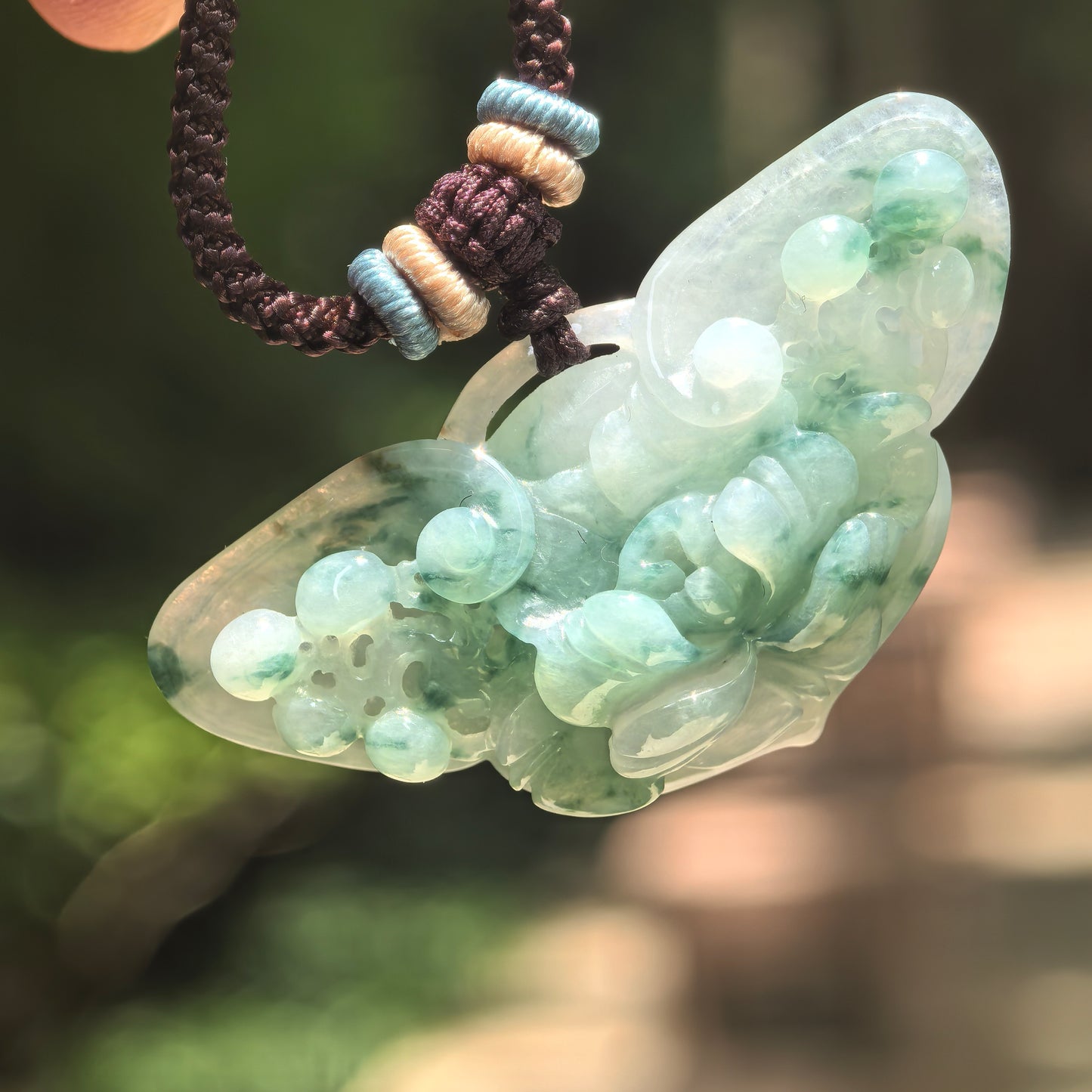 Natural untreated Burmese jadeite pendant with darker green floating flower patterns and polished luster.
