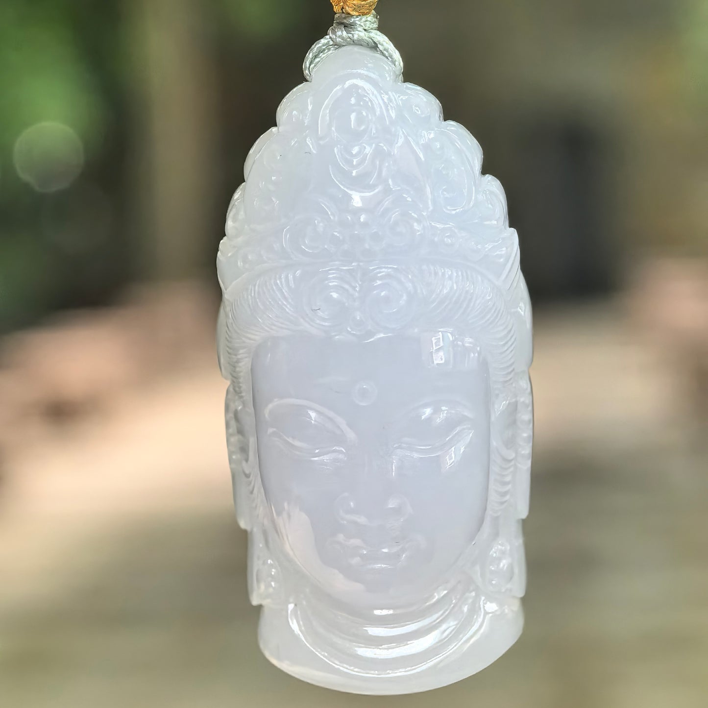 Natural Grade-A glutinous pale lavender Buddha head jadeite pendant hanging in natural light.
