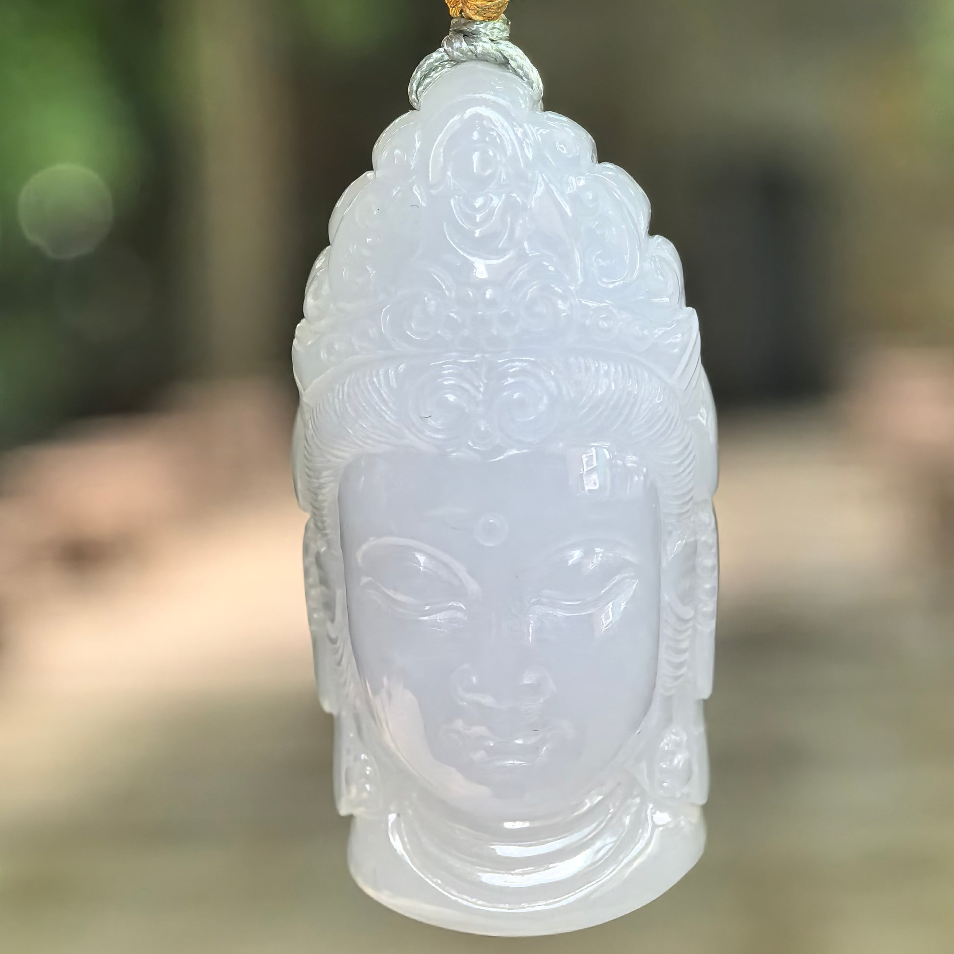 Natural Grade-A glutinous pale lavender Buddha head jadeite pendant hanging in natural light.
