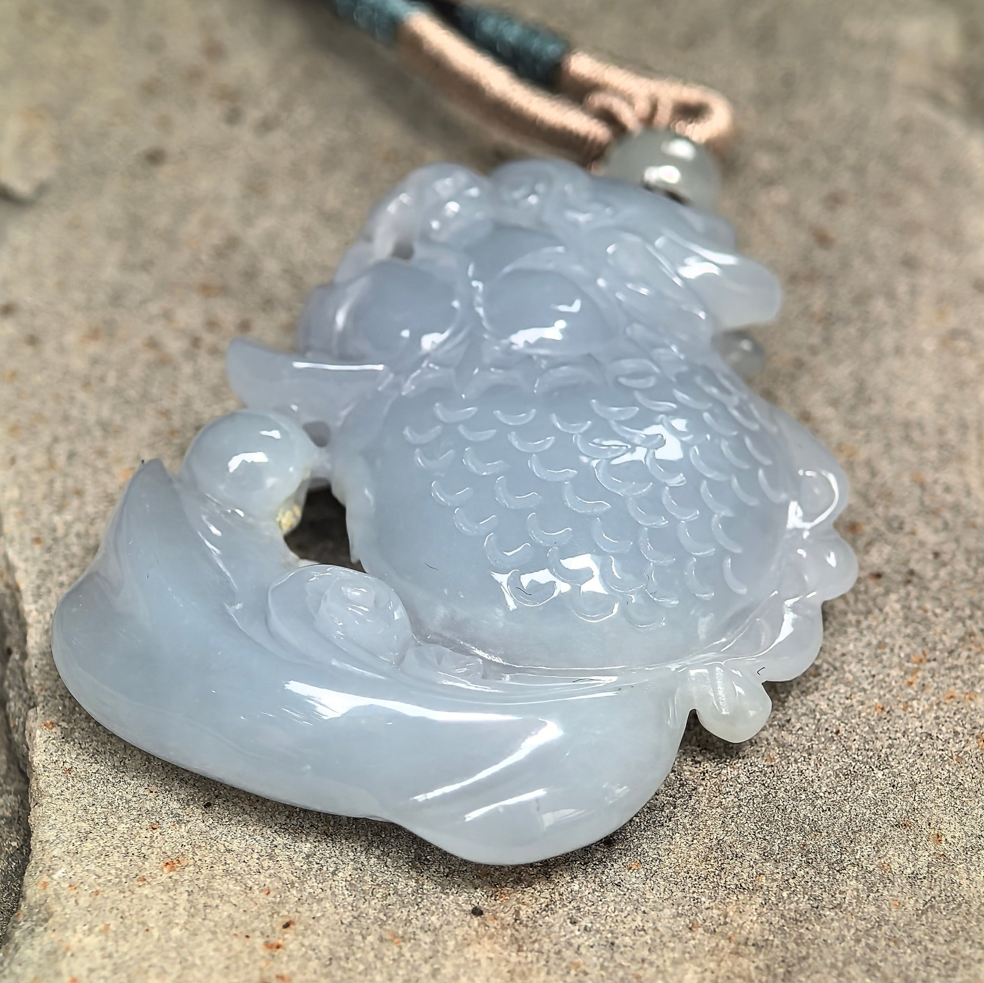 Natural untreated jadeite pendant with pale lavender color, smooth luster, and detailed carving.
