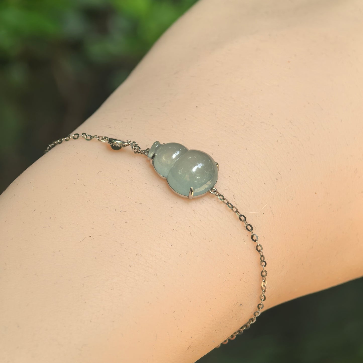 Natural Grade-A icy light green gourd jadeite 18K gold bracelet worn on wrist.
