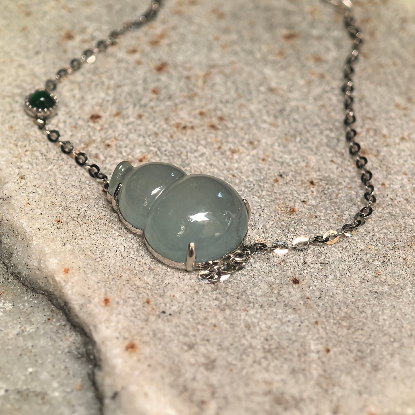 Elegant light green jadeite bracelet with gourd-shaped center and delicate chain detail.
