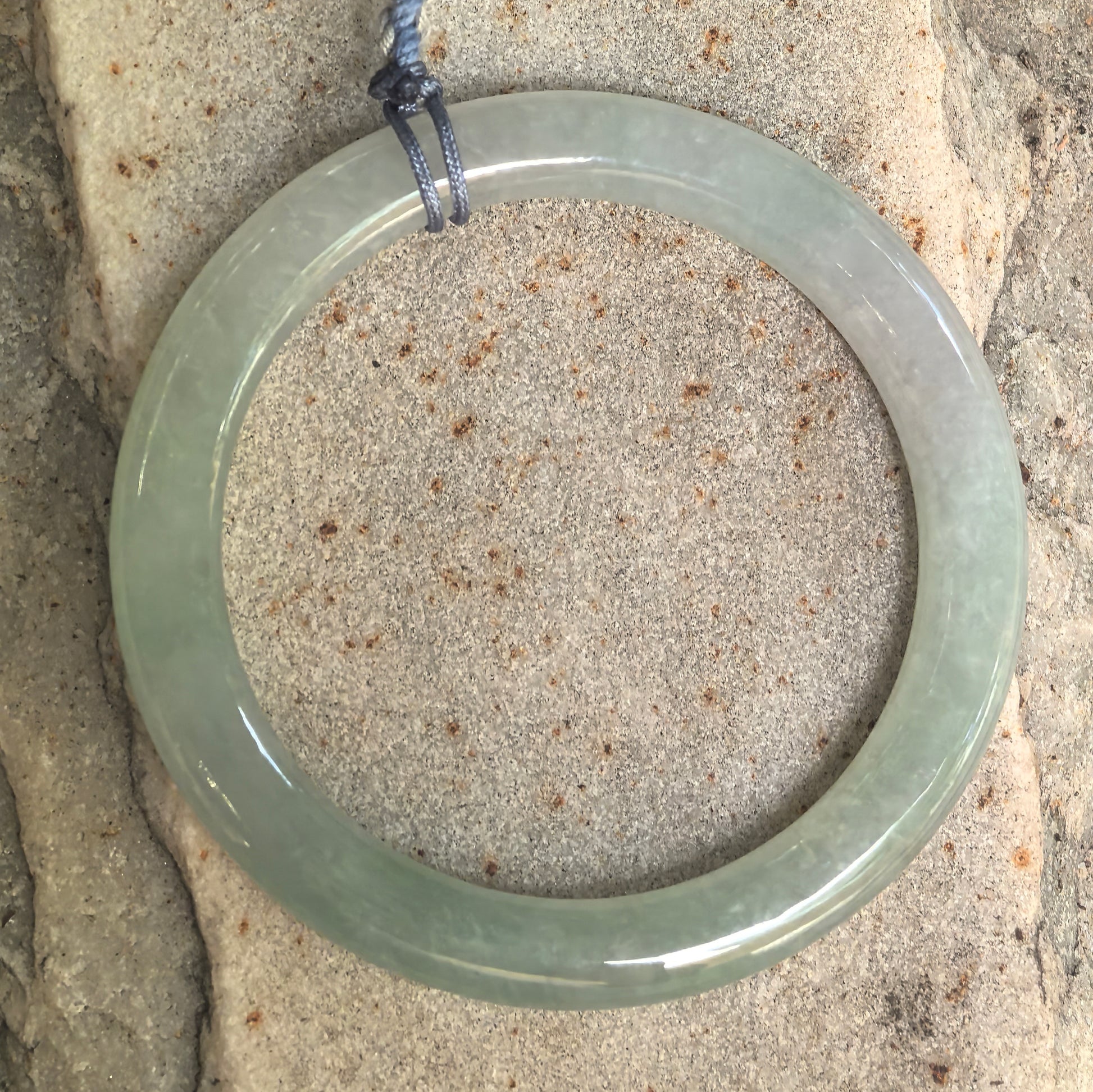 Top view of small light green jadeite bangle showing round ring shape and smooth polished surface.
