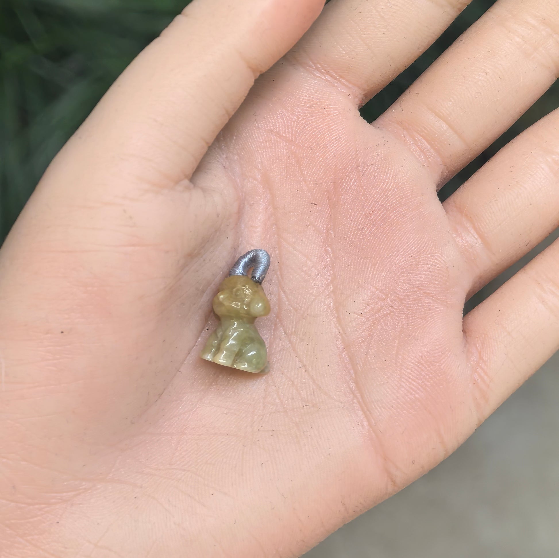 Petite natural jadeite puppy charm shown in hand for size reference.

