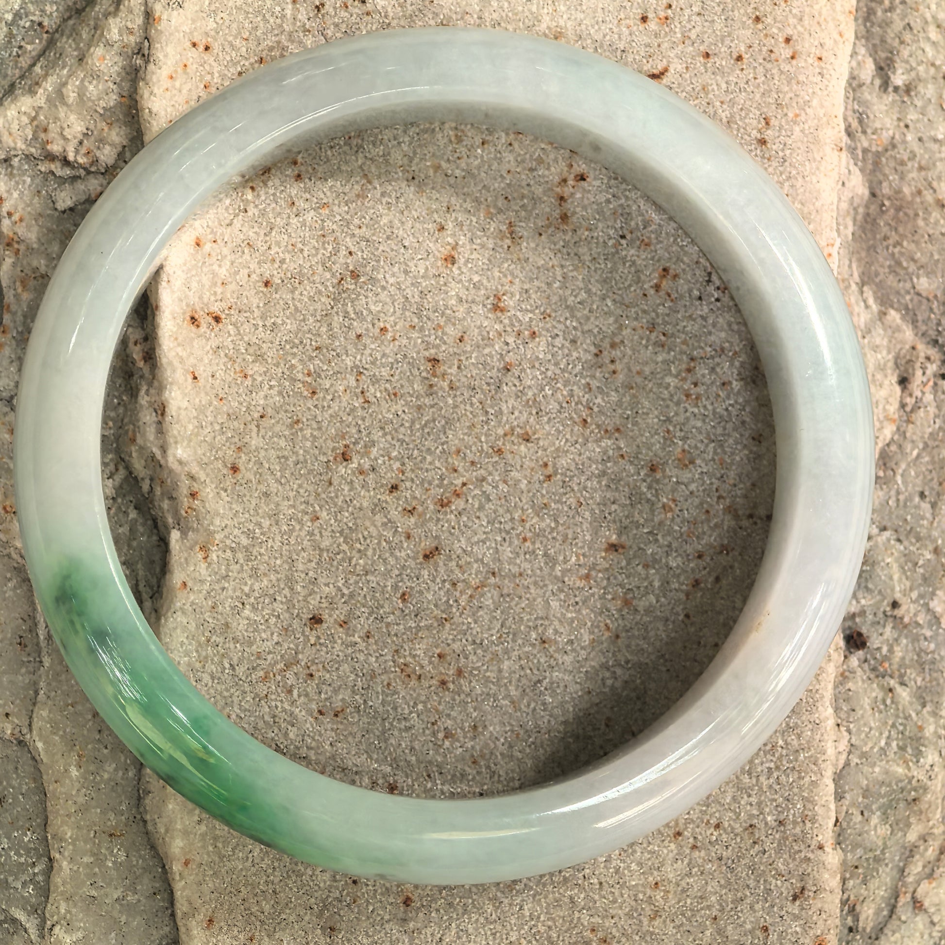 Top view of Natural Grade-A jadeite bangle showing D-shape form and green-white color contrast.
