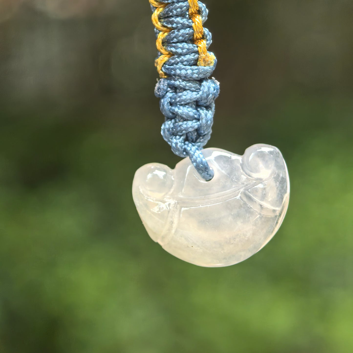 Natural Grade-A icy glutinous white ingot jadeite bag charm hanging on blue woven cord.
