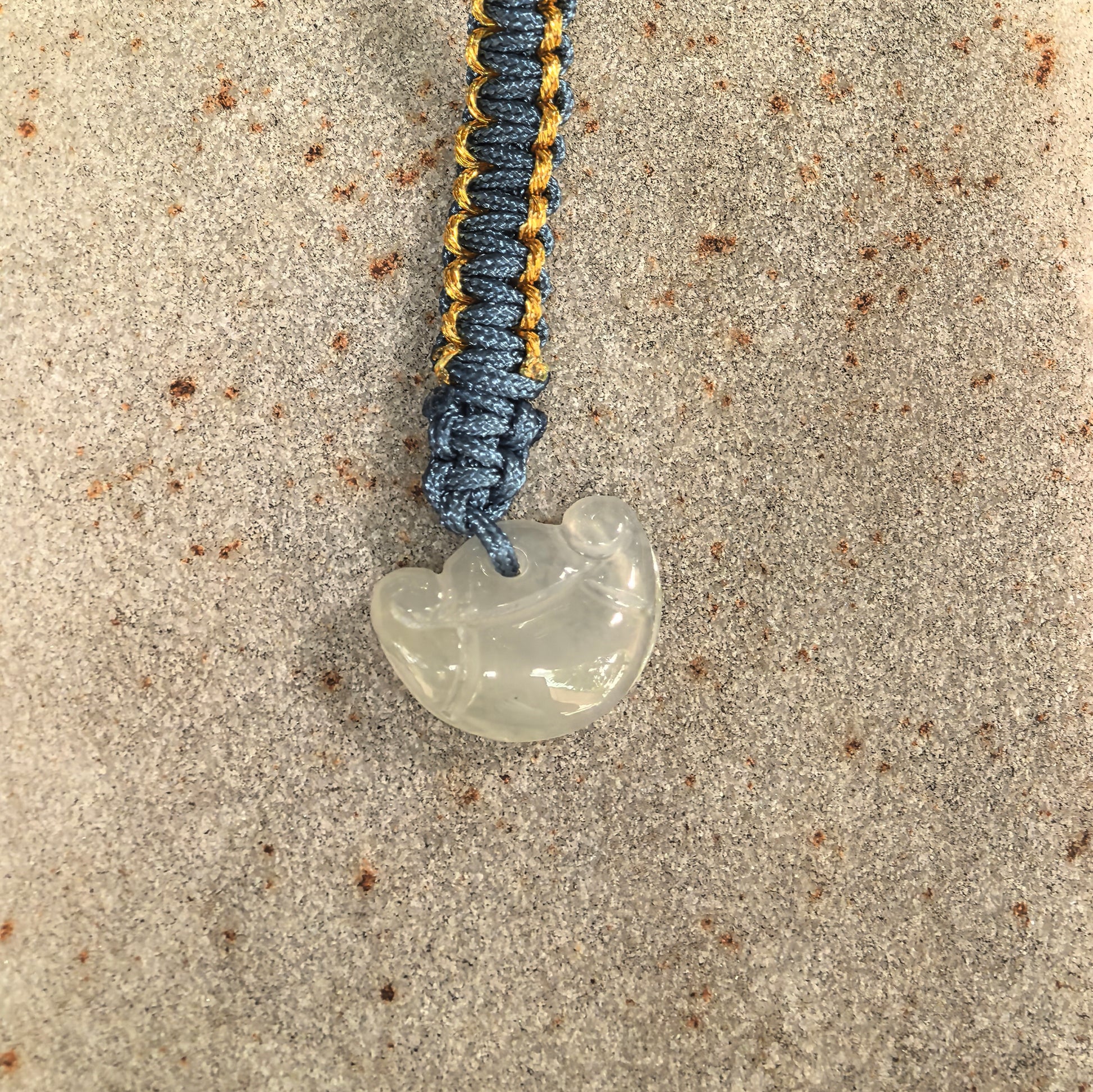 Close-up of white ingot jadeite pendant showing rounded carving and glossy icy-glutinous texture.
