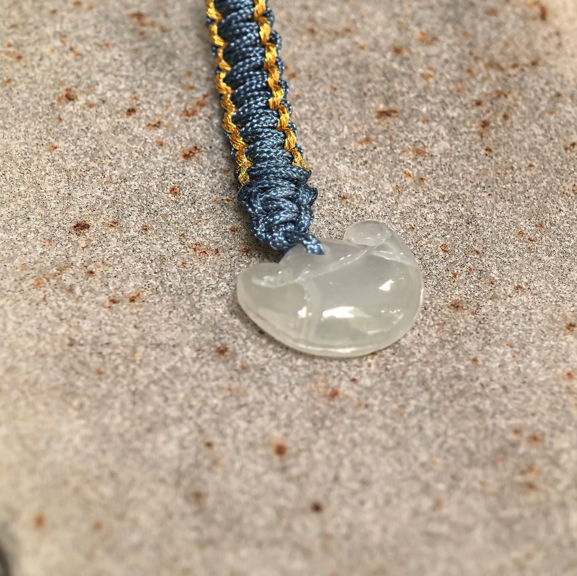 Side view of small white jadeite bag charm showing slim thickness and smooth carved form.
