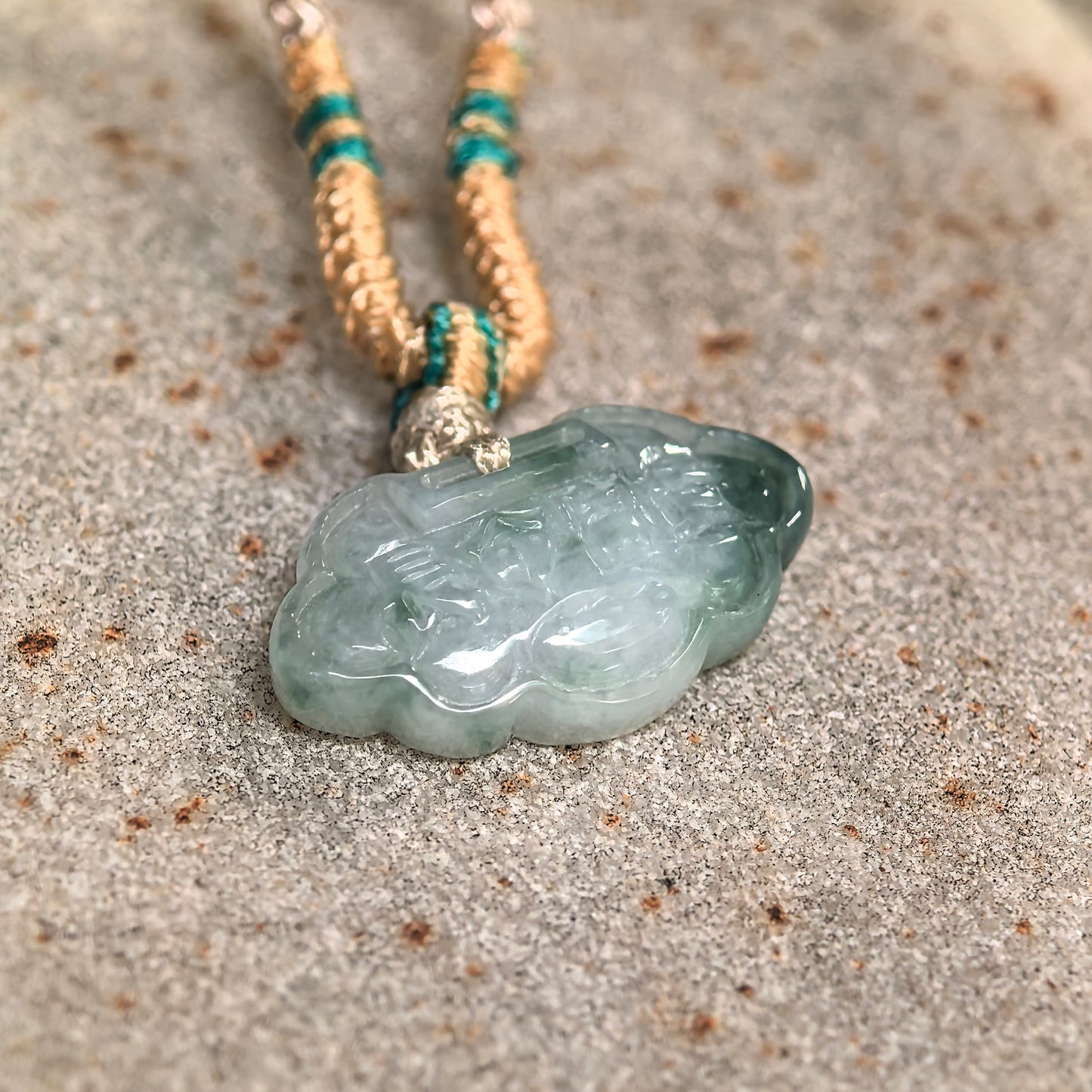 Close-up of carved cloud lock jadeite pendant showing soft glutinous texture and natural green accent.
