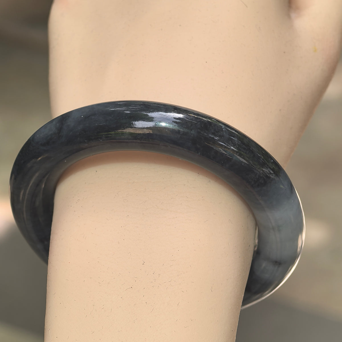 Close-up of black-gray jadeite bangle showing glossy luster and cloud-like natural texture.
