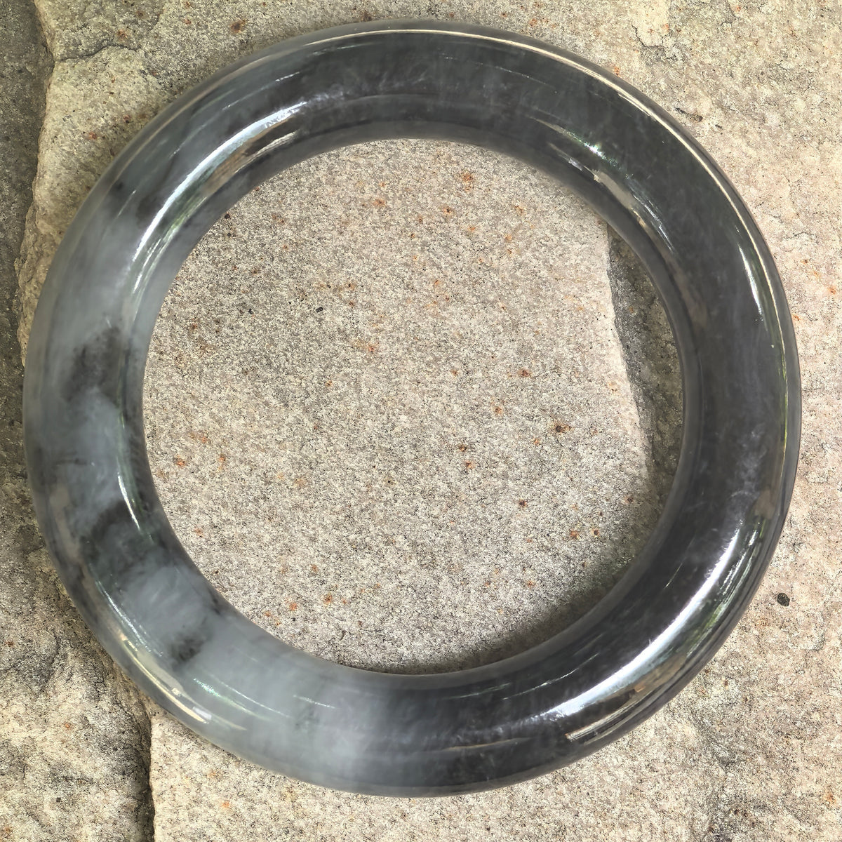 Black-gray Burmese jadeite bangle with glutinous texture and polished rounded profile.
