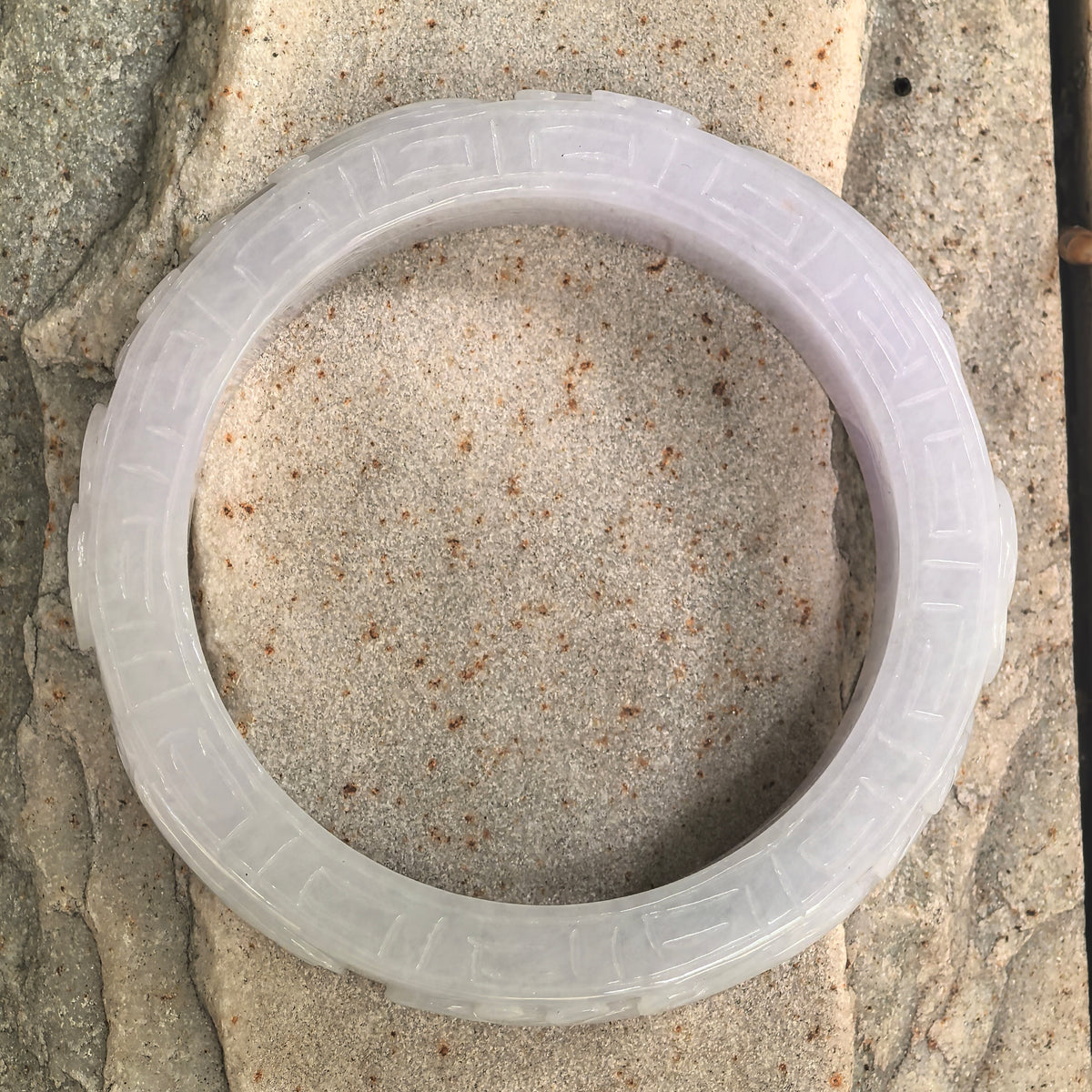 NGTC certified white glutinous jadeite bangle with D-shape structure and carved outer surface.