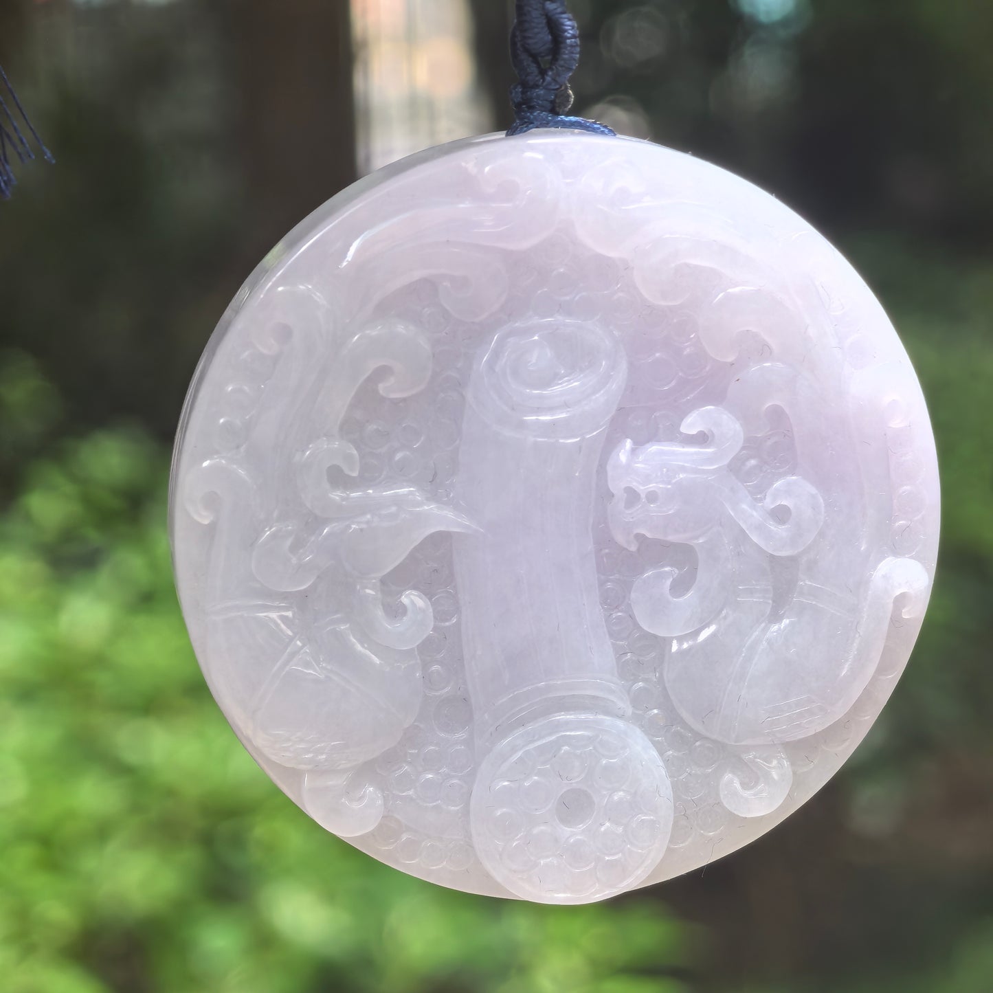Natural Grade-A glutinous white carved jadeite feng shui ornament hanging on dark cord.
