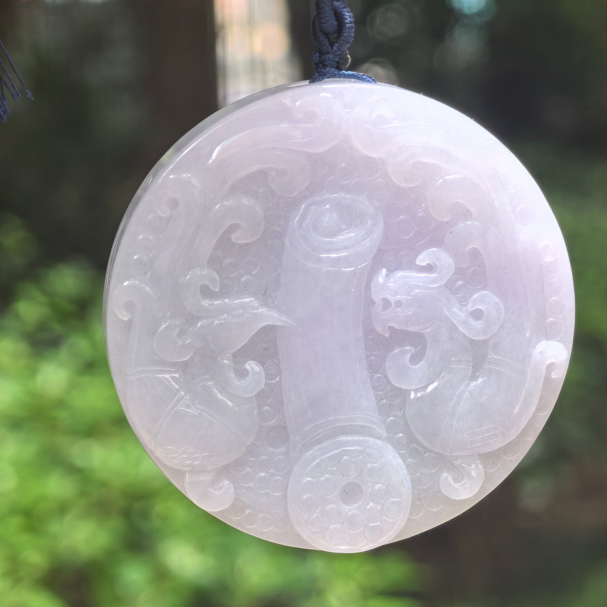 Natural Grade-A glutinous white carved jadeite feng shui ornament hanging on dark cord.
