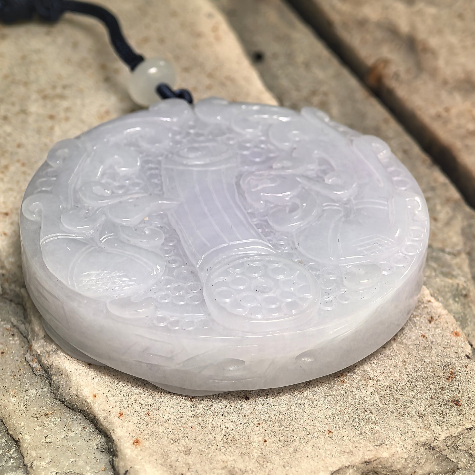 Side view of glutinous white jadeite ornament showing thick round profile and polished surface.
