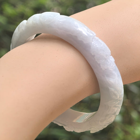 Natural Grade-A glutinous white carved D-shape jadeite bangle worn on wrist with soft glossy luster.
