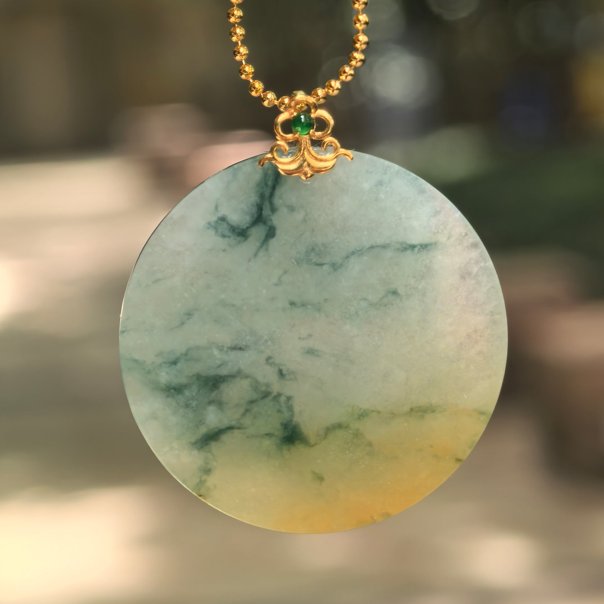 Natural Grade-A icy glutinous yellow-green round jadeite pendant with 18K gold bail hanging on chain.
