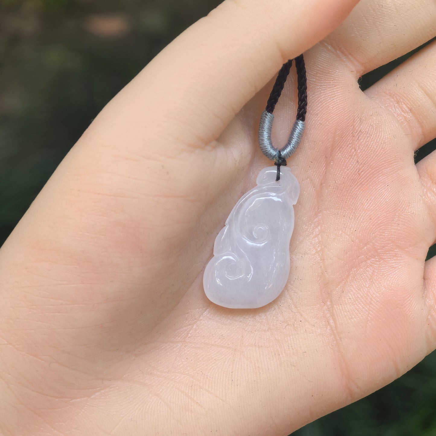 Hand-held view showing the size and smooth shape of the natural Grade-A white jadeite pendant.