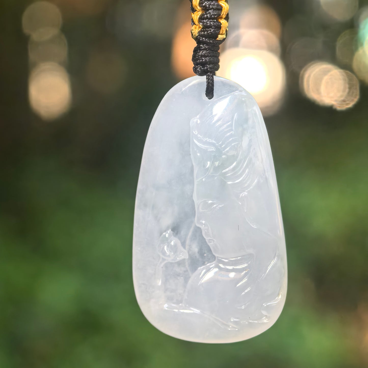 Natural Grade-A icy-glutinous white Guanyin jadeite pendant hanging from a woven cord in natural light.