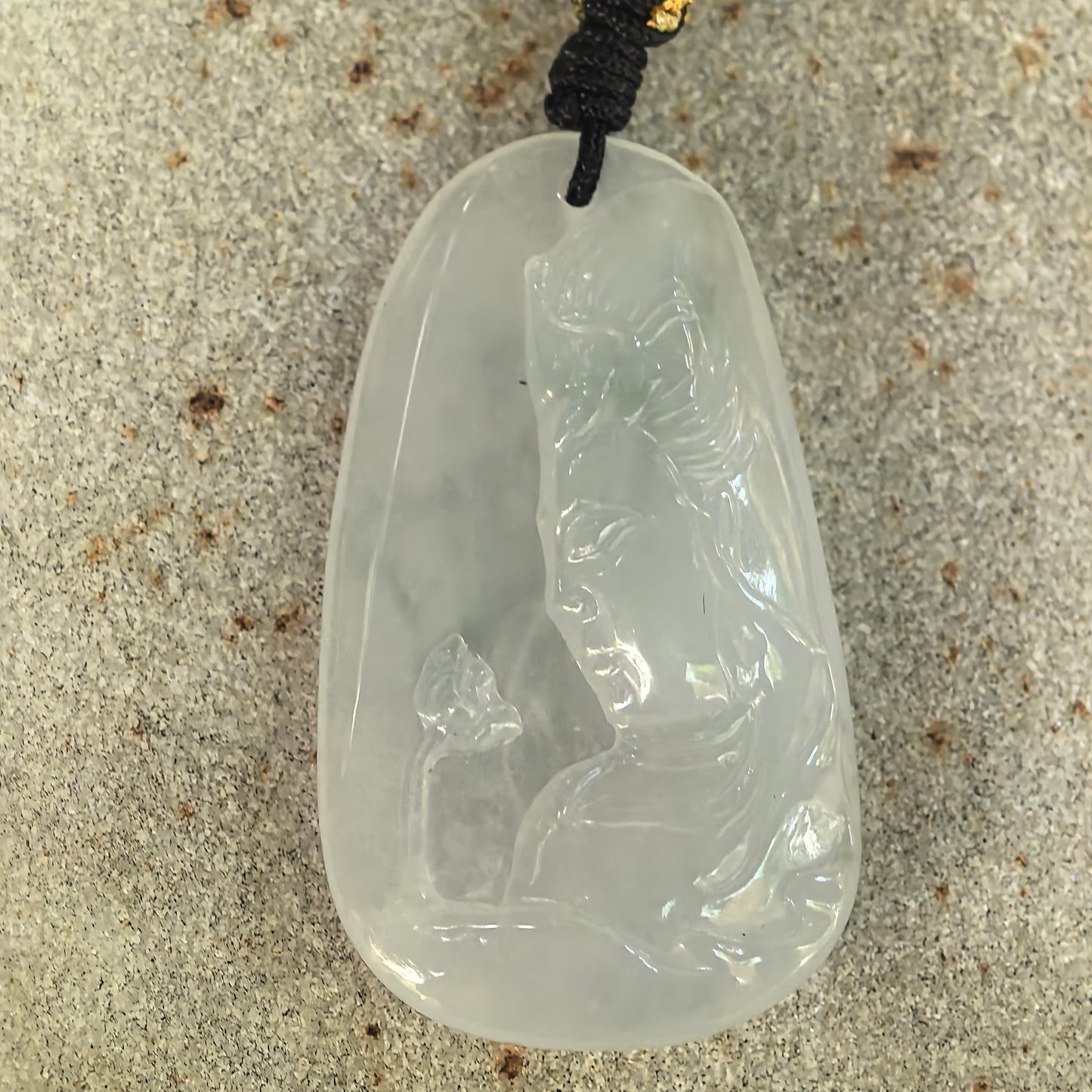 Front detail view of an icy-glutinous white jadeite pendant carved with a standing Guanyin figure.
