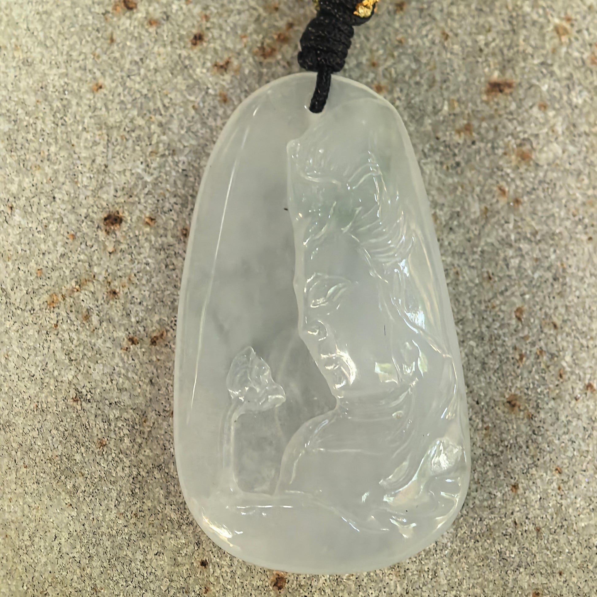 Front detail view of an icy-glutinous white jadeite pendant carved with a standing Guanyin figure.