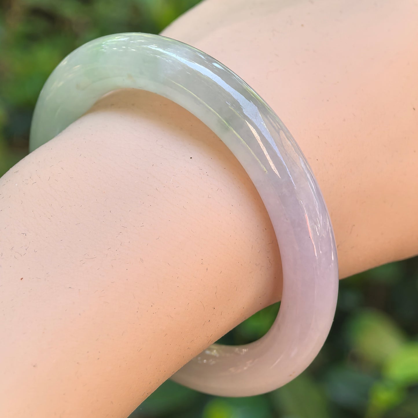 Natural Grade-A icy glutinous lavender and green jadeite round bangle worn on the wrist, showing its smooth polished surface.