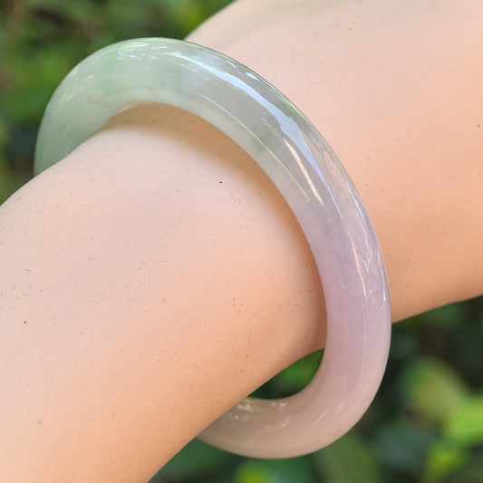 Natural Grade-A icy glutinous lavender and green jadeite round bangle worn on the wrist, showing its smooth polished surface.