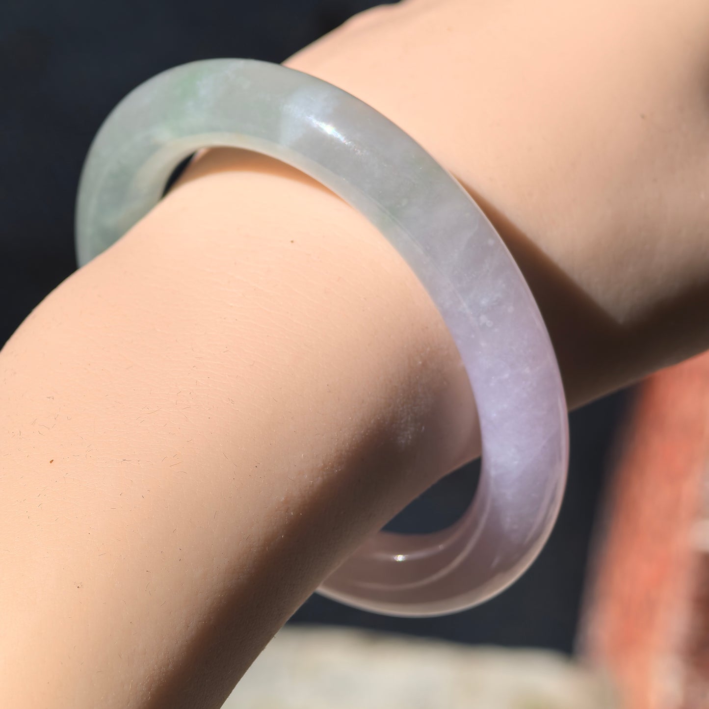 NGTC-certified icy glutinous jadeite bangle shown in sunlight, highlighting the concentrated lavender color and natural texture.