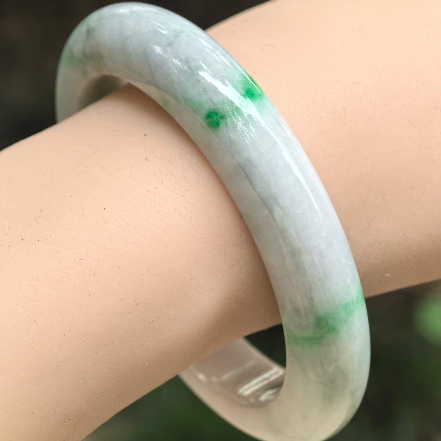 Natural Grade-A bean-glutinous pale green jadeite bangle worn on the wrist with vivid green spots and bands.