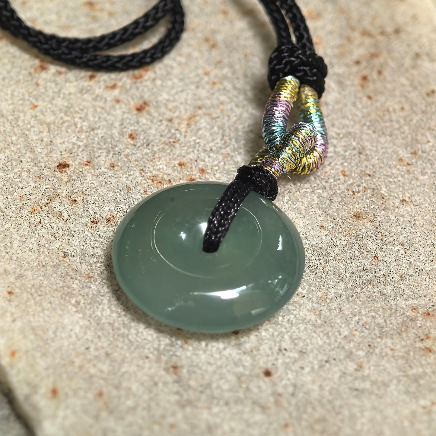 Close-up of a deep green jadeite Peace Pendant with icy-gel translucency and smooth concentric contours.