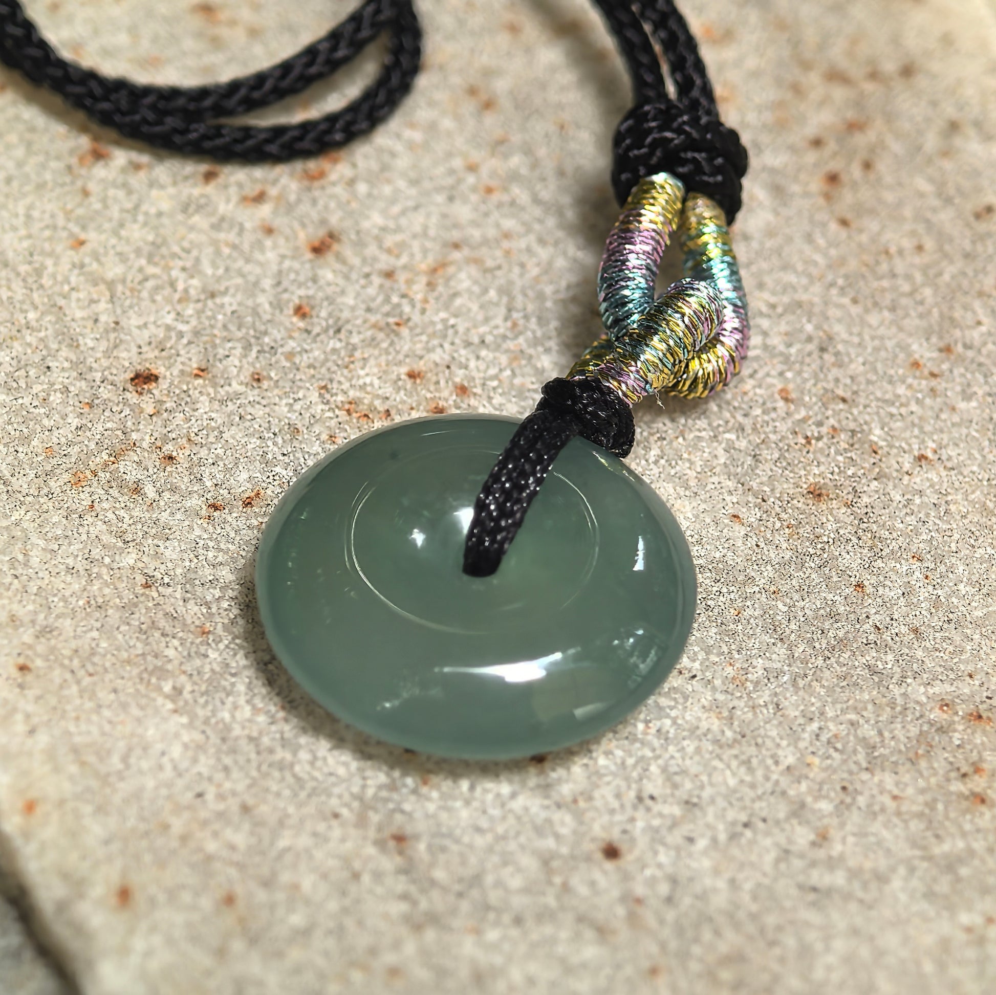 Close-up of a deep green jadeite Peace Pendant with icy-gel translucency and smooth concentric contours.