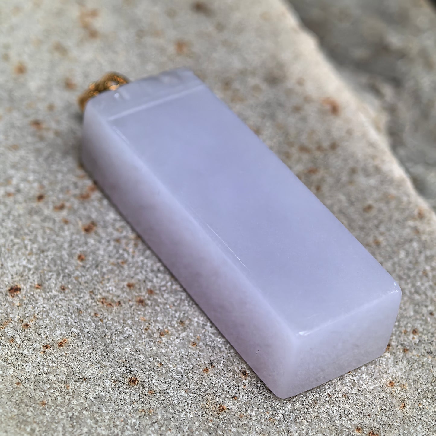 Close-up of the icy-glutinous lavender jadeite column pendant showing its even texture, rounded edges, and soft luster.