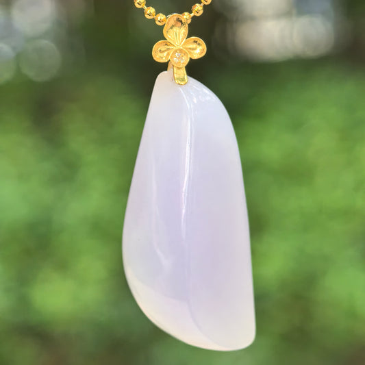 Natural Grade-A icy-glutinous pale lavender freeform jadeite pendant with an 18K gold floral bail hanging in natural light.