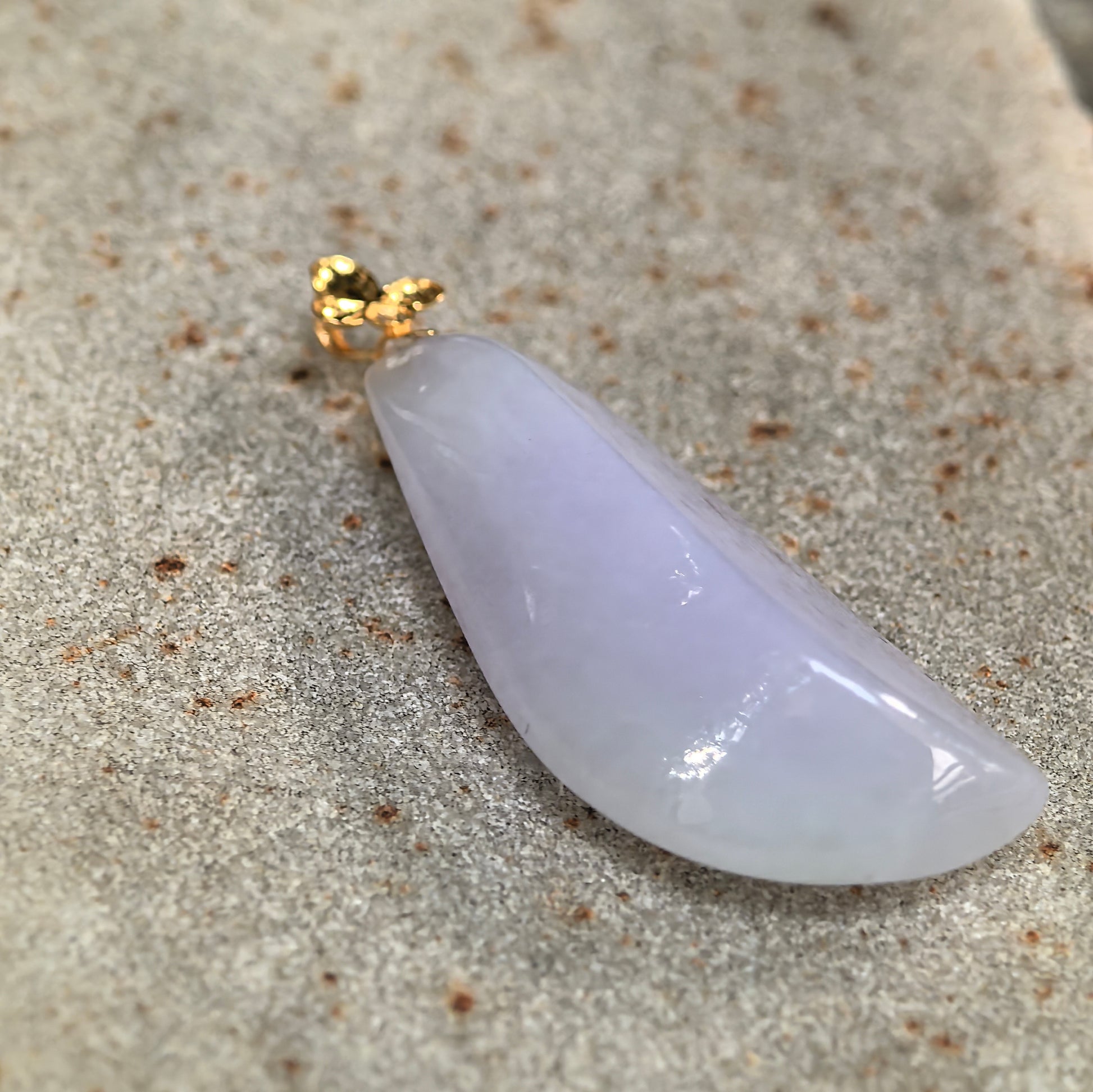 Side-angle close-up of the icy-glutinous lavender jadeite pendant showing its substantial thickness and rounded profile.