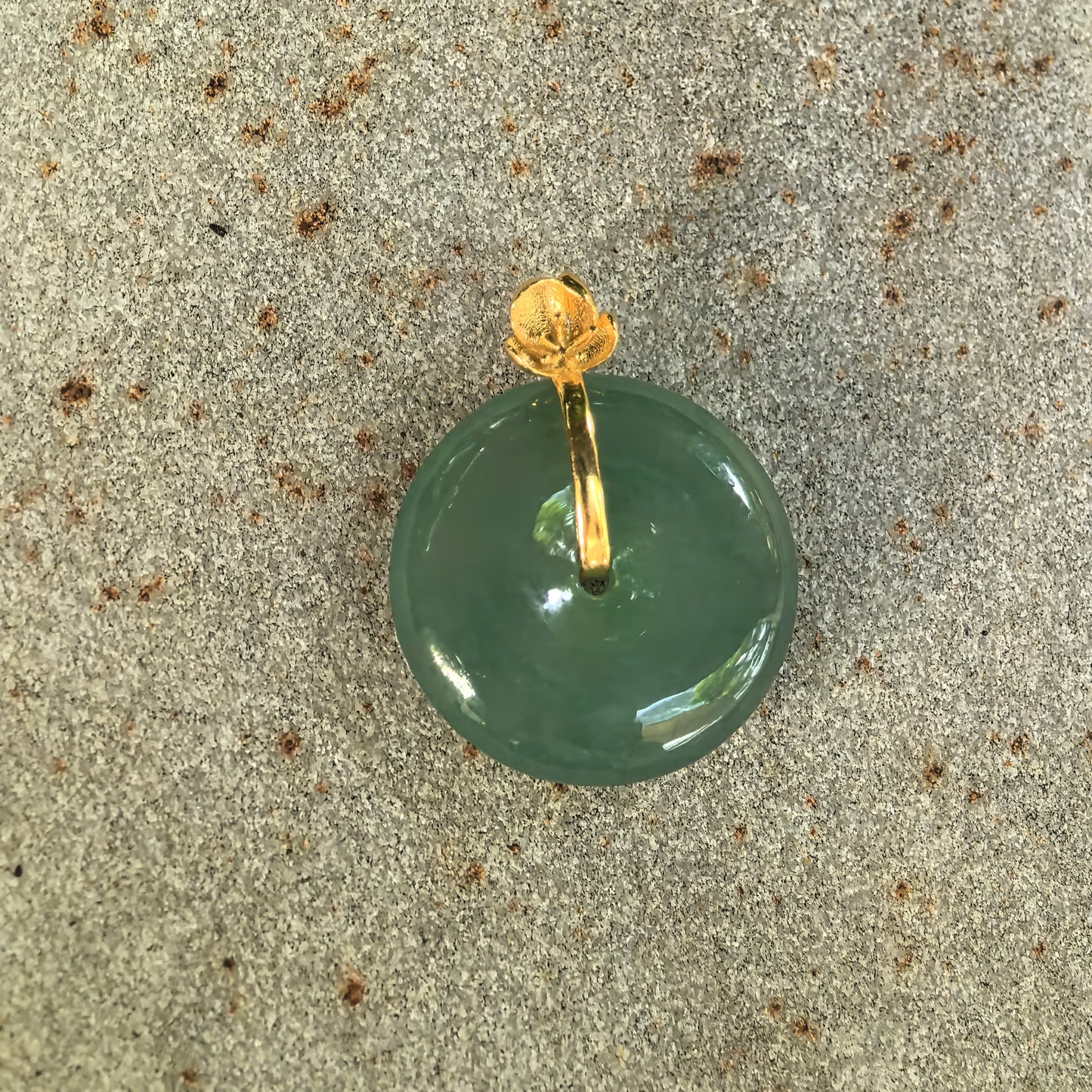 Top view of the icy glutinous green jadeite Peace Pendant showing its central opening and flower-shaped 18K gold bail.