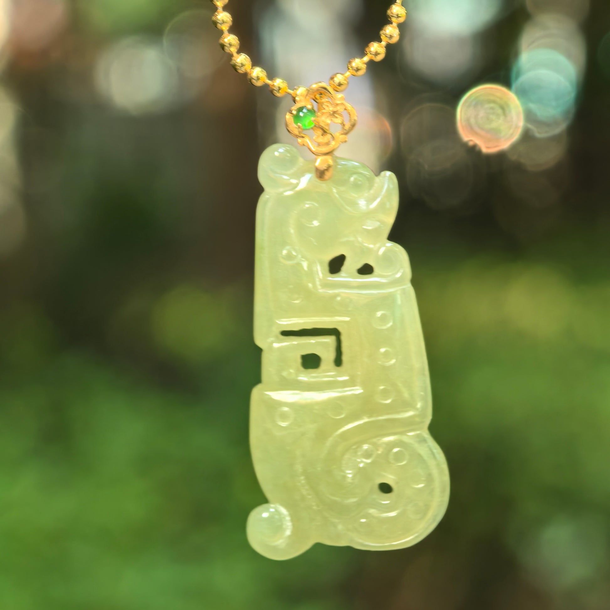 Natural Grade-A icy glutinous yellow-green Kui dragon jadeite pendant hanging from a gold-tone chain with an 18K gold floral bail.