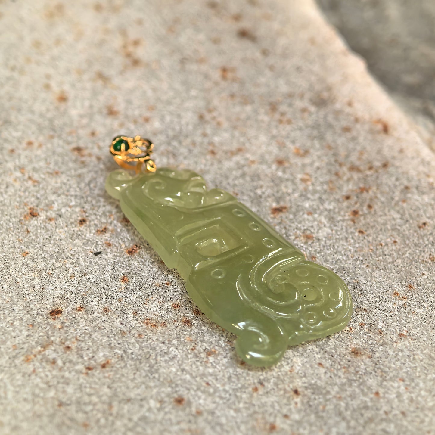 Close-up side view of the icy glutinous jadeite pendant showing its slim profile, openwork details, and polished surface.