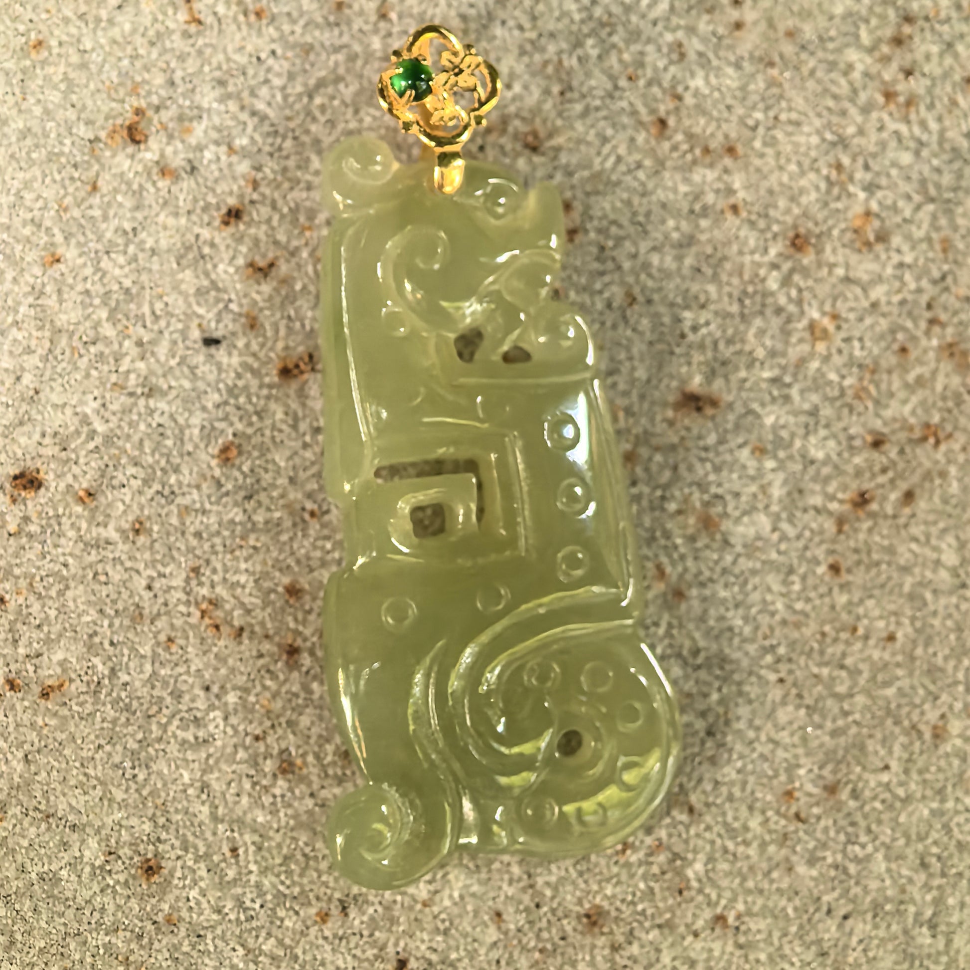 NGTC-certified yellow-green jadeite Kui dragon pendant displayed with its matching certificate and 18K gold fitting.