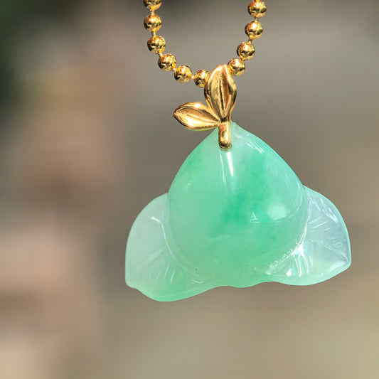 Natural Grade-A icy glutinous green peach jadeite pendant with an 18K gold leaf bail hanging from a gold-tone chain.