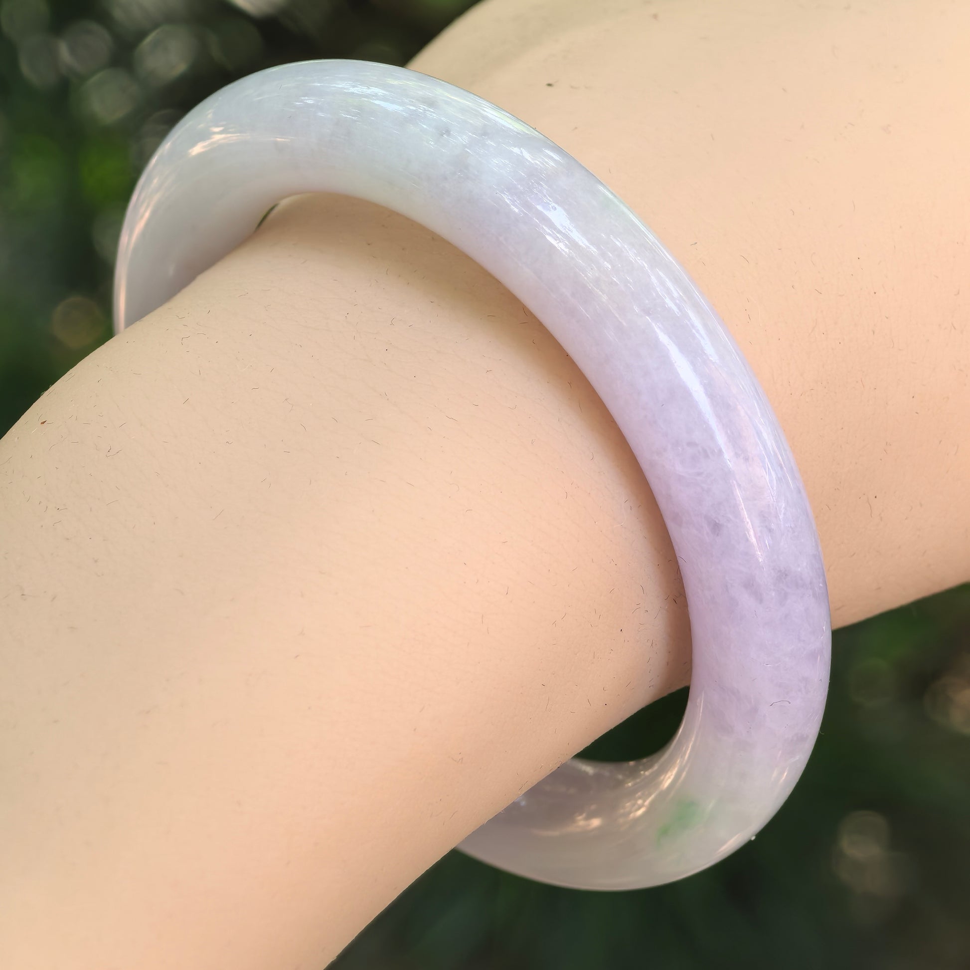 Natural Grade-A glutinous light lavender and green jadeite round-bar bangle worn on the wrist.