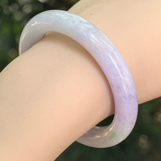 Natural Grade-A glutinous light lavender and green jadeite round-bar bangle worn on the wrist.
