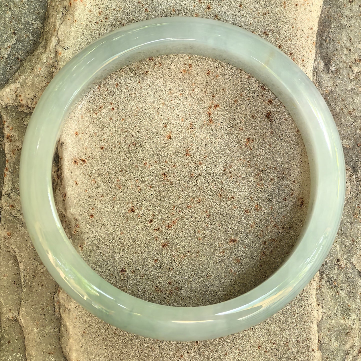 Top view of a polished glutinous light green jadeite bangle showing its classic D-shape structure.