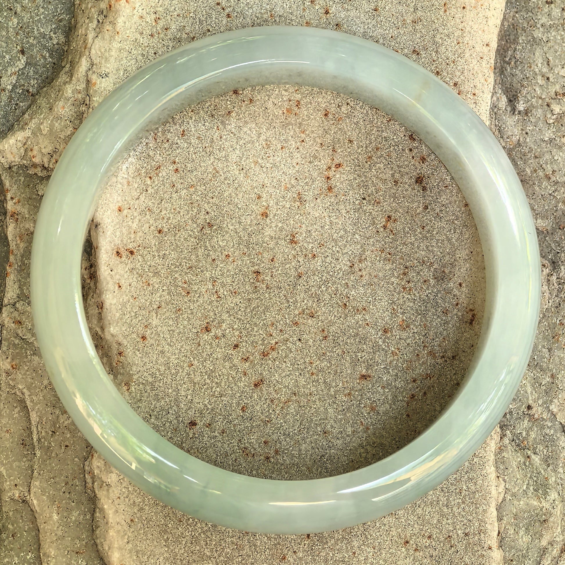 Top view of a polished glutinous light green jadeite bangle showing its classic D-shape structure.