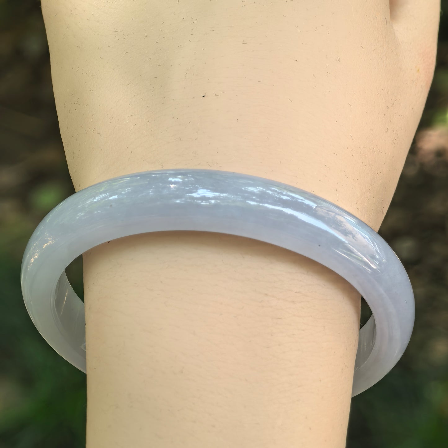 Close-up of a Natural Grade-A icy glutinous blue-lavender jadeite oval bangle worn on the wrist.